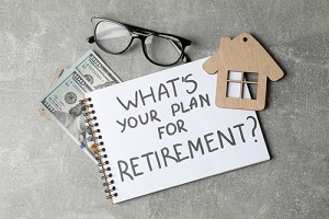 notebook with inscription, glasses, wood house and money on grey background, top view