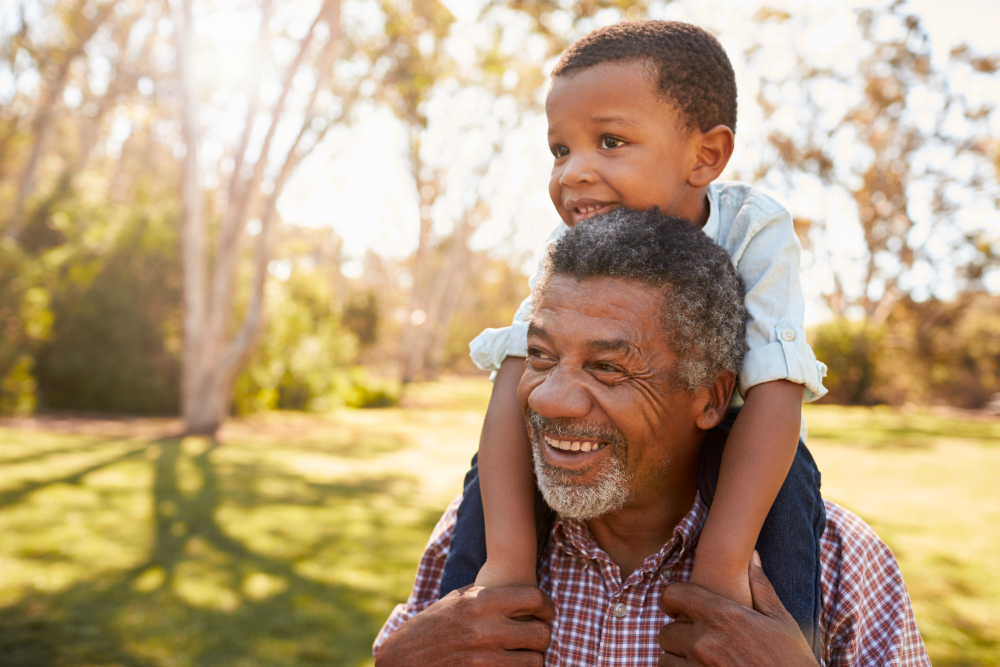 grandfather with grandchild on his shoulders outside