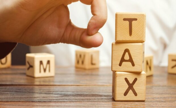 businessman removes wooden blocks with the word tax