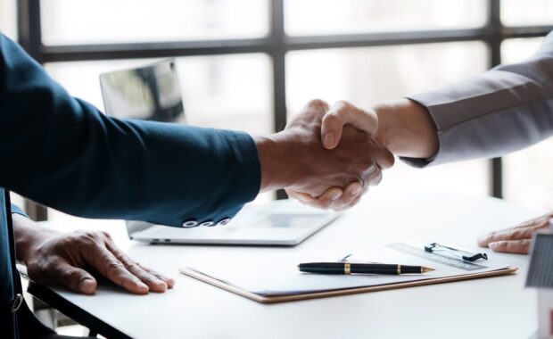estate agent shakes hands with a client to sign a home purchase contract congratulating the client on the purchase
