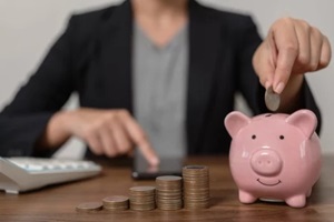 the thrifty businessman puts coins in a pink pig shaped savings box